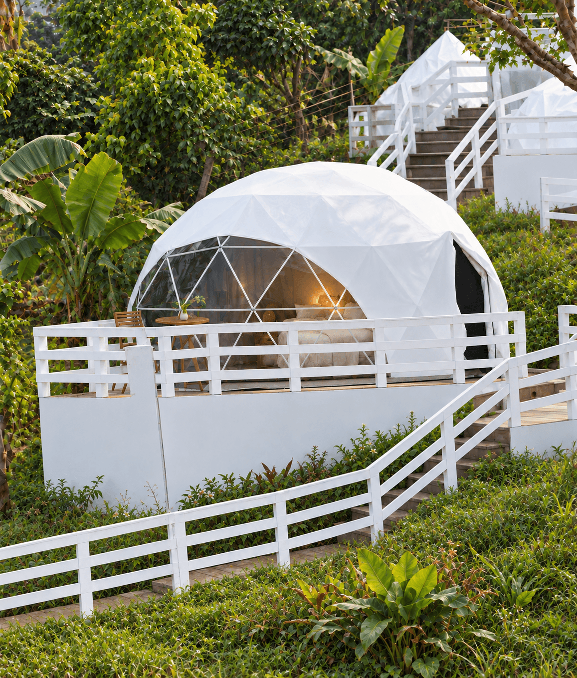 Superior Dome exterior, a white glamping dome on a raised deck on a green hillside