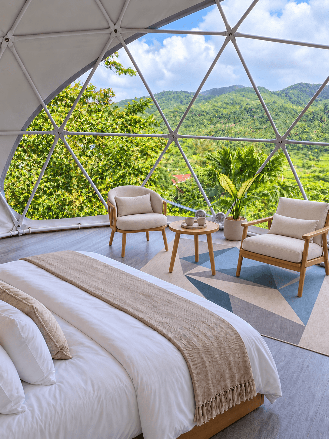 Superior Dome interior with a queen bed, two armchairs and a glass wall facing the mountains