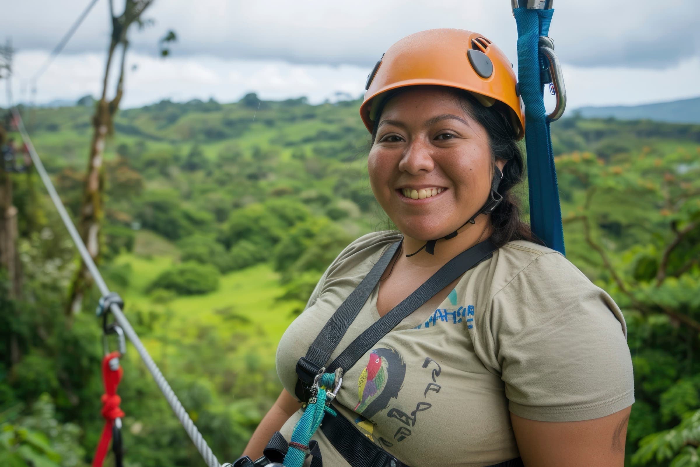 Smiling guest in a helmet and harness on the zip line above green hills